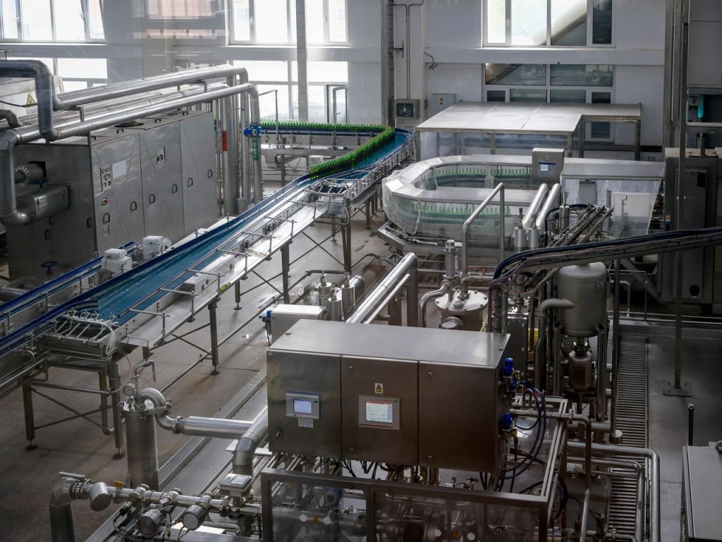 Botol air minum melewati checkweigher air minum pada lini pengemasan